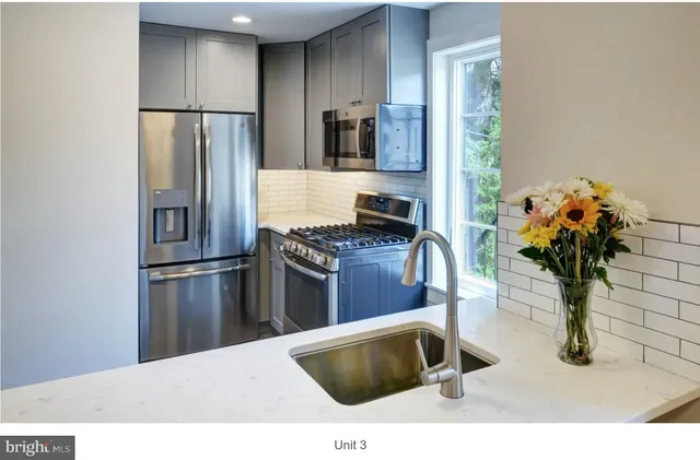 a kitchen with stainless steel appliances kitchen island granite countertop a refrigerator and a sink