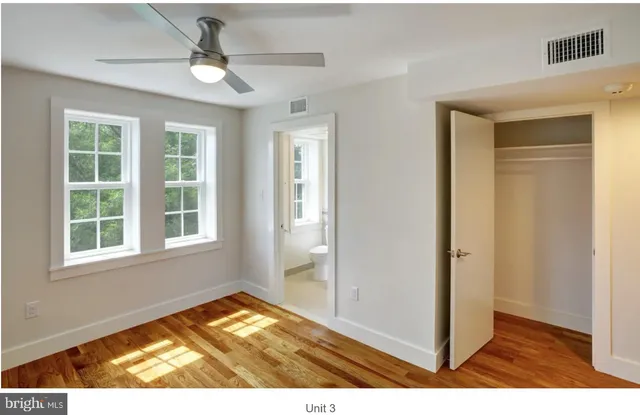 a view of empty room with wooden floor and fan