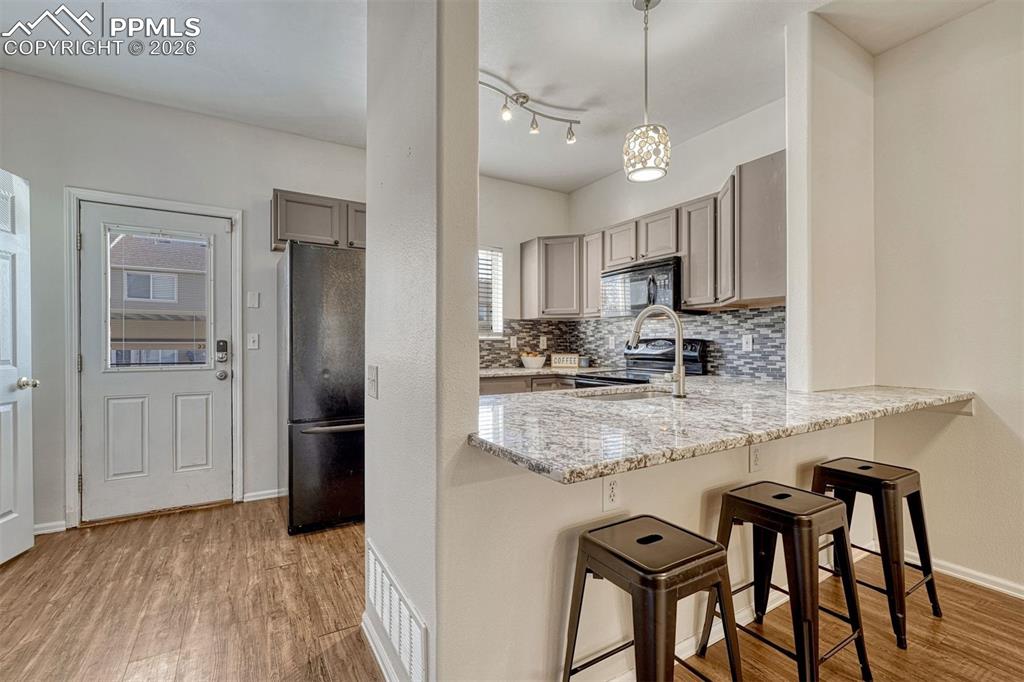 2580 Malpaso Point Colorado Springs, CO 80922 - Photo 8 of 23 a kitchen with stainless steel appliances granite countertop a refrigerator a sink dishwasher a stove and white cabinets with wooden floor