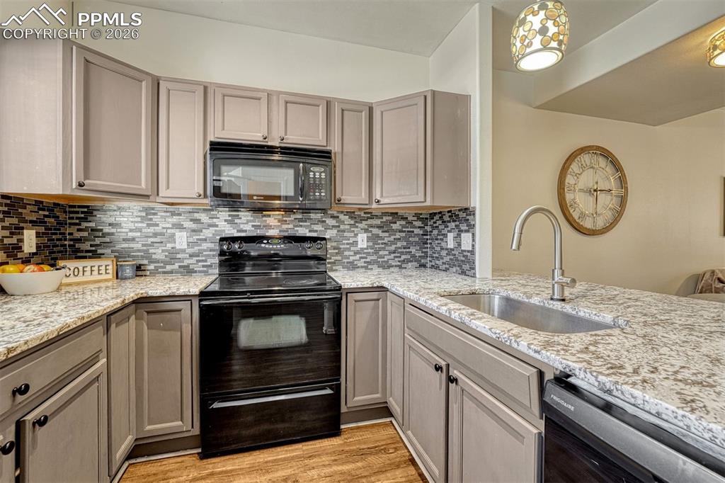 2580 Malpaso Point Colorado Springs, CO 80922 - Photo 9 of 23 a kitchen with granite countertop a stove a sink and a microwave