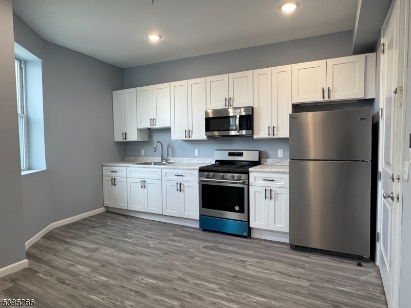 a kitchen with a refrigerator stove and white cabinets