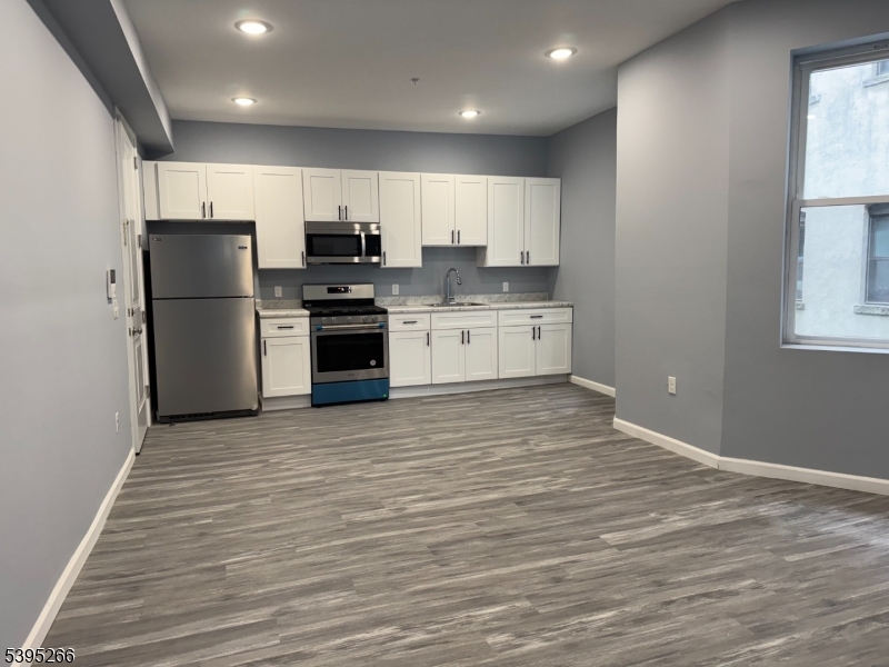 155 Clifton Avenue, Unit 3RR Newark, NJ 07104 - Photo 4 of 13 a kitchen with stainless steel appliances granite countertop a refrigerator sink and stove