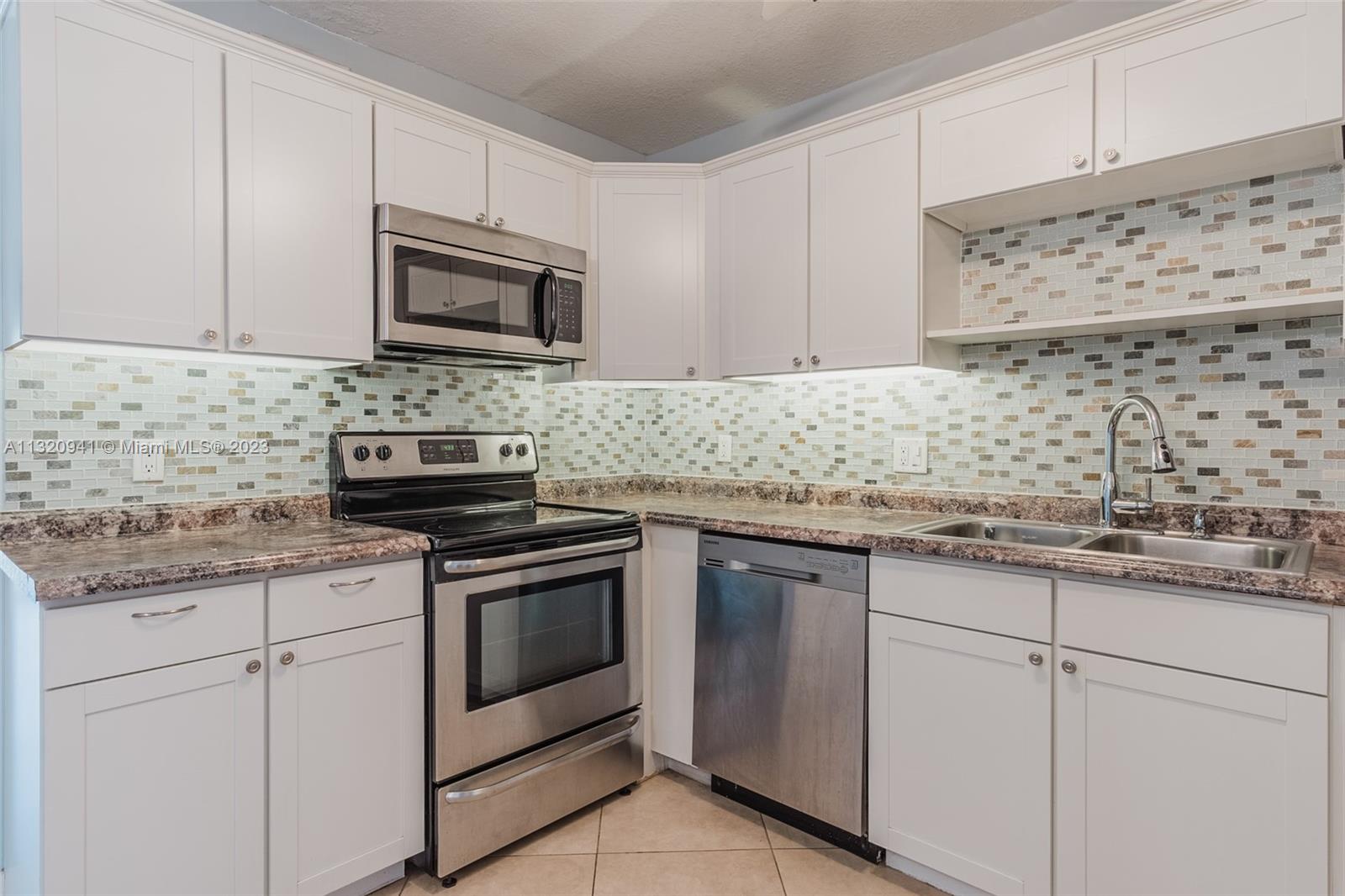 Jacaranda Plantation, FL 33324 - Photo 2 of 22 a kitchen with granite countertop white cabinets and stainless steel appliances