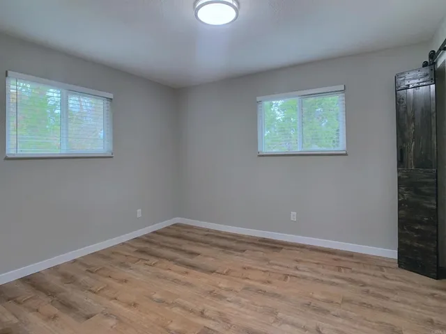 a view of an empty room with wooden floor and a window