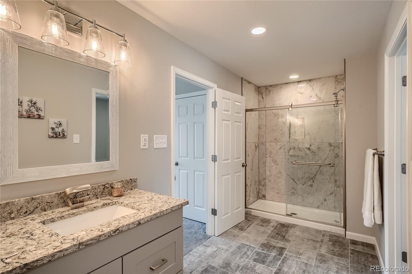 8506 Eaton Street Arvada, CO 80003 - Photo 16 of 28 a bathroom with a granite countertop sink mirror and shower