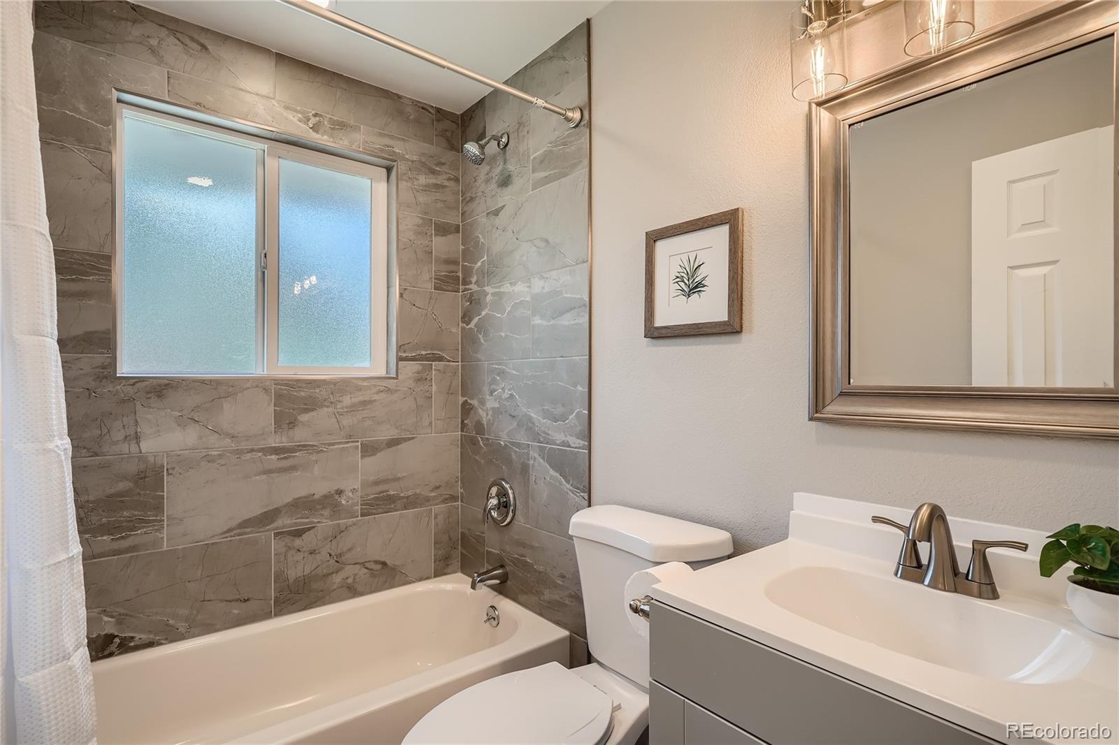 8506 Eaton Street Arvada, CO 80003 - Photo 18 of 28 a bathroom with a sink mirror vanity and toilet