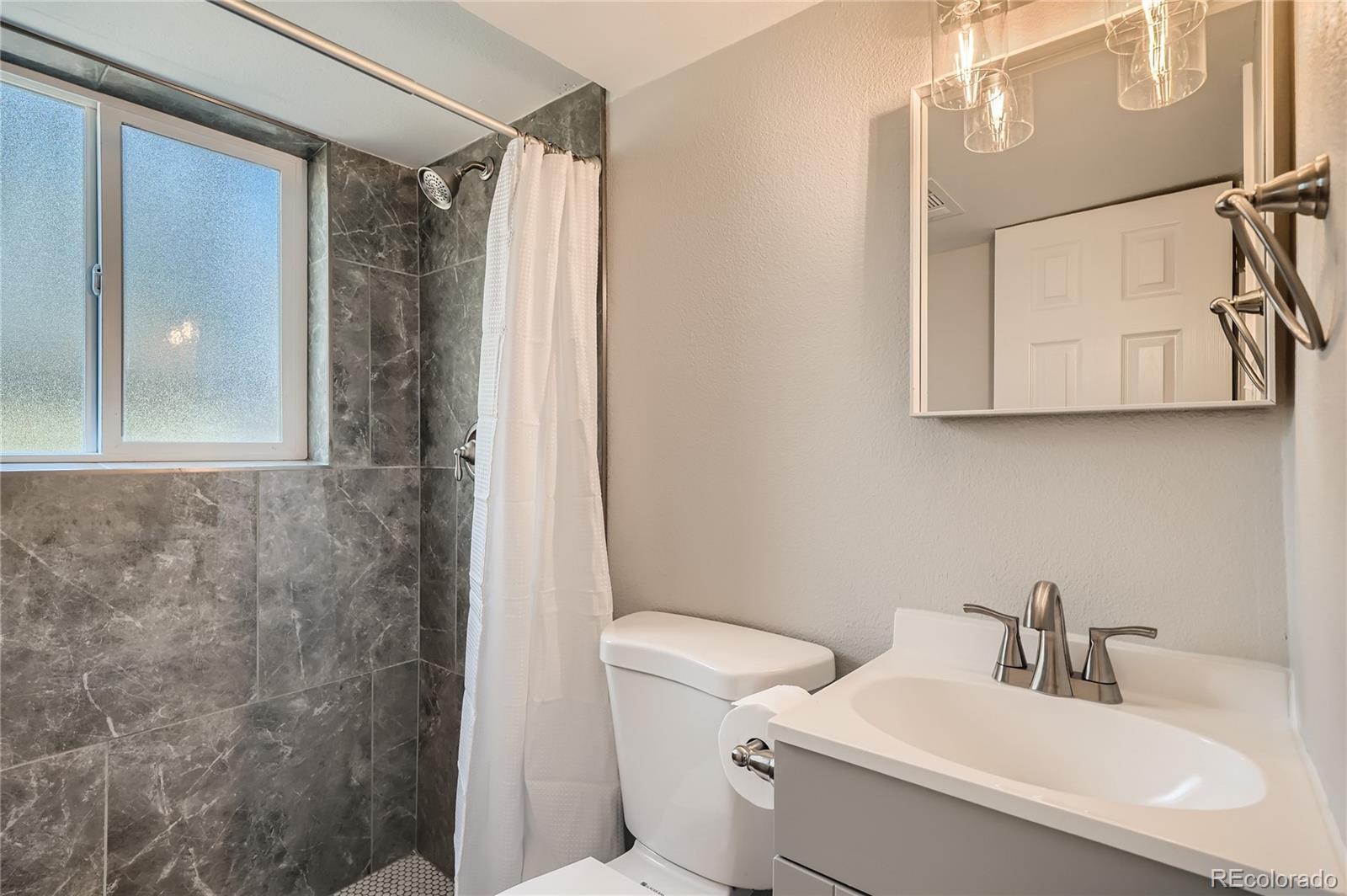8506 Eaton Street Arvada, CO 80003 - Photo 21 of 28 a bathroom with a sink a toilet and shower