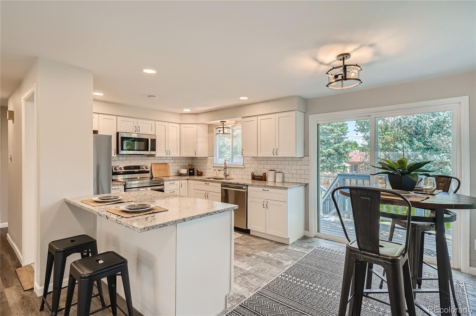 8506 Eaton Street Arvada, CO 80003 - Photo 7 of 28 a kitchen with stainless steel appliances granite countertop a stove a sink dishwasher a stove a refrigerator with a dining table and chairs