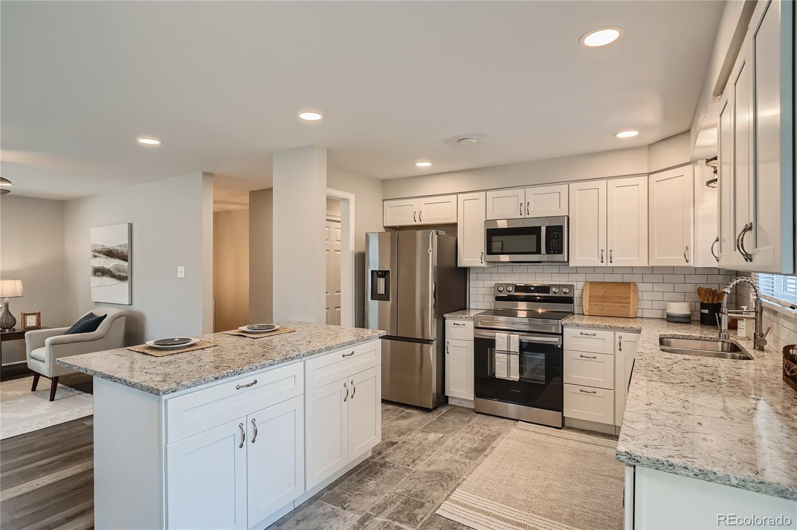 8506 Eaton Street Arvada, CO 80003 - Photo 8 of 28 a kitchen with stainless steel appliances granite countertop a sink stove refrigerator and cabinets