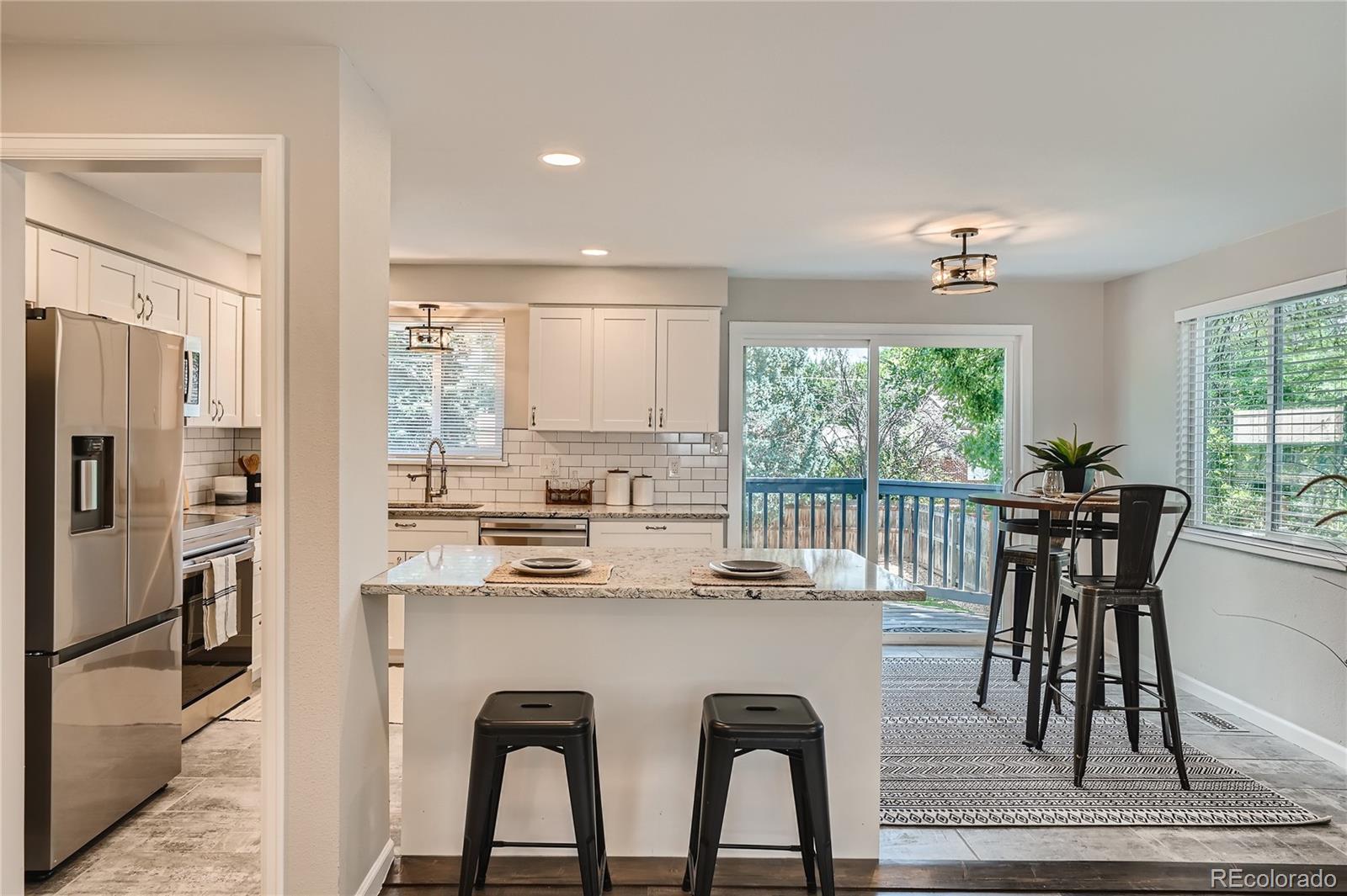 8506 Eaton Street Arvada, CO 80003 - Photo 10 of 28 a kitchen with stainless steel appliances granite countertop a dining table chairs and refrigerator