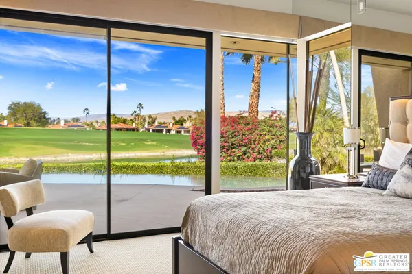 a bedroom with a bed and large windows