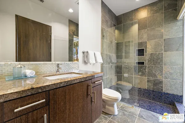 a bathroom with a granite countertop sink toilet and shower