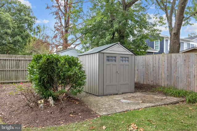 a view of a small house with a tree and wooden fence