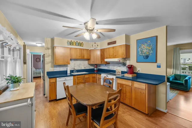 a kitchen with stainless steel appliances granite countertop a stove a sink dishwasher a dining table and chairs with wooden floor