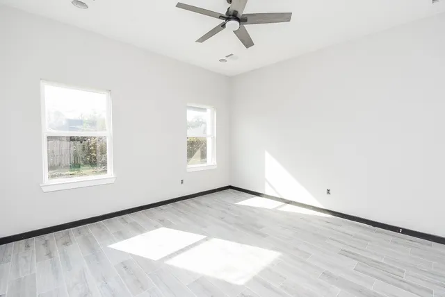 an empty room with windows and fan
