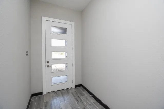 a view of an empty room with a window and wooden floor