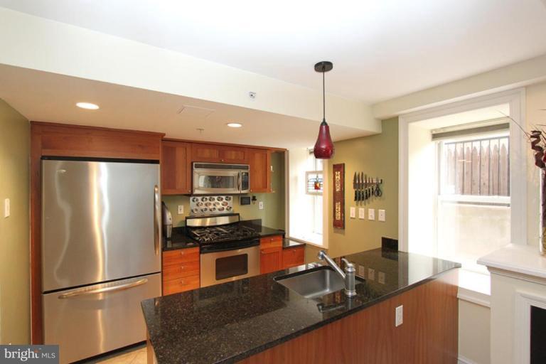1750 16th Street Northwest, Unit 4 Washington, DC 20009 - Photo 7 of 20 a kitchen with stainless steel appliances granite countertop a refrigerator a stove and a sink with wooden floor