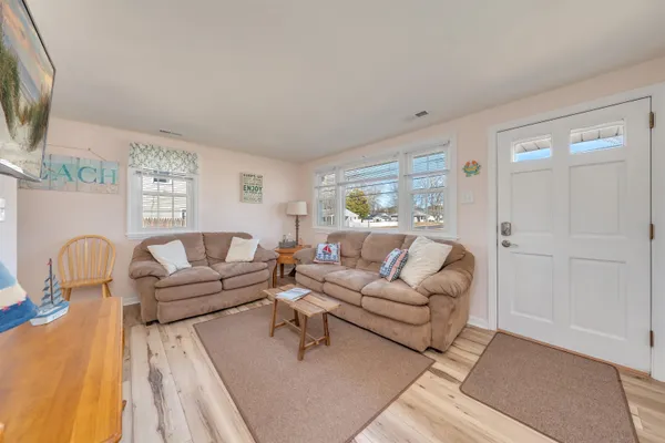 a open kitchen with stainless steel appliances kitchen island granite countertop a refrigerator a stove a dining table and chairs with wooden floor