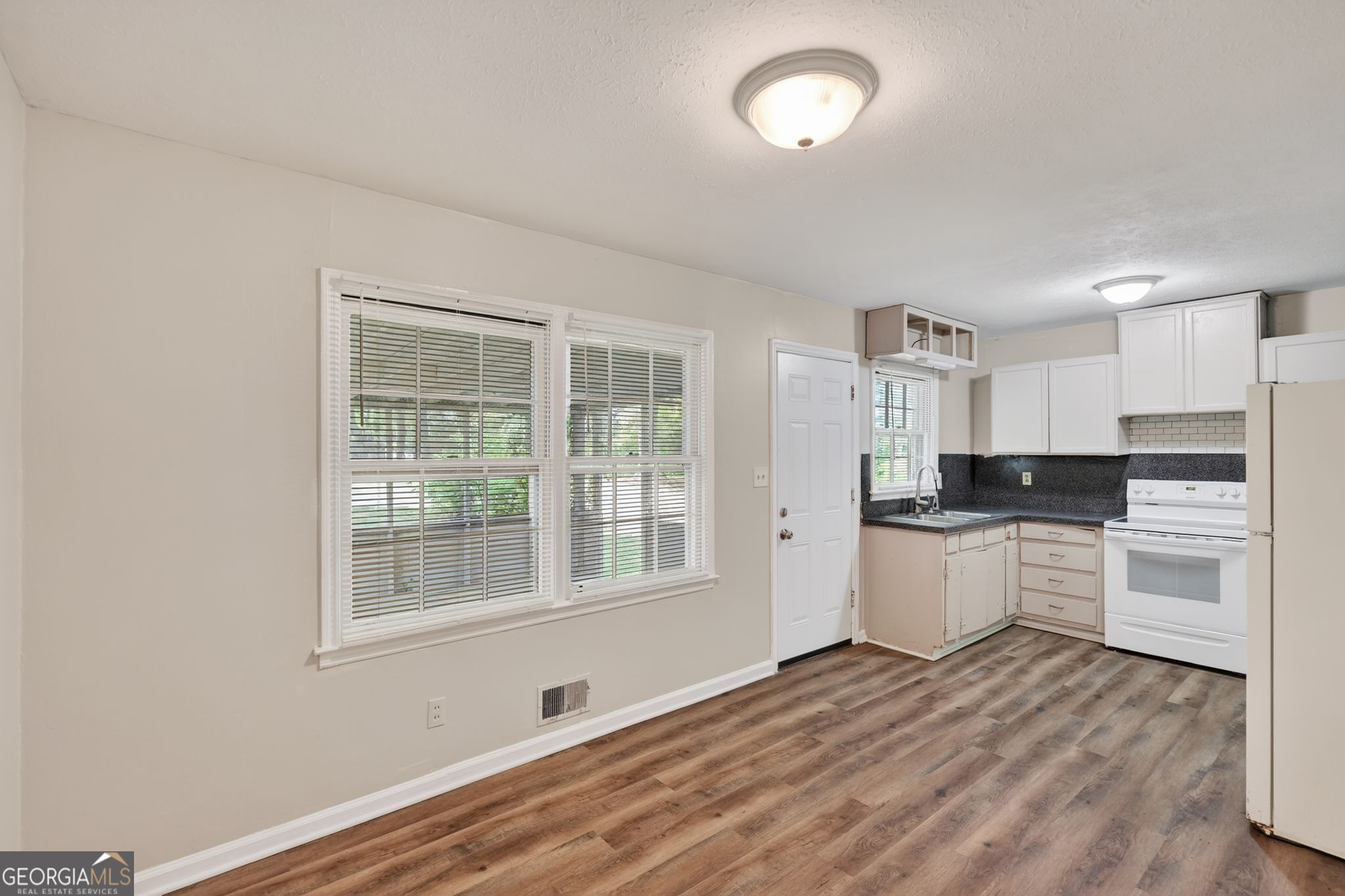 1071 Luther Drive Southwest Mableton, GA 30126 - Photo 15 of 27 a kitchen with a refrigerator and white cabinets