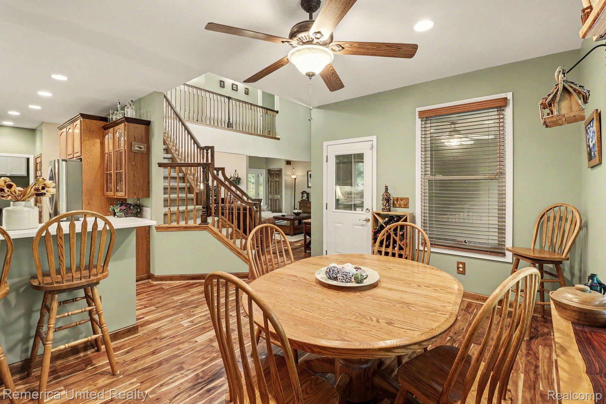 20962 Wasson Road Gregory, MI 48137 - Photo 9 of 39 Open-concept dining area featuring wood-finish flooring, a ceiling fan with integrated lighting, and a white paneled door with glass insert