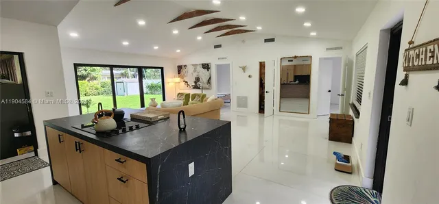 a kitchen with kitchen island granite countertop a sink and a refrigerator