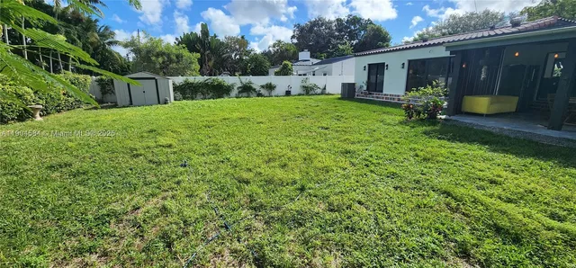 a view of a backyard with sitting area and tree
