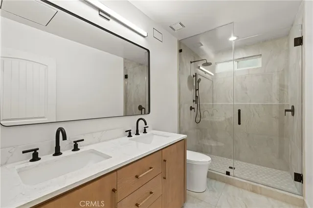 a bathroom with a double vanity sink toilet mirror and shower