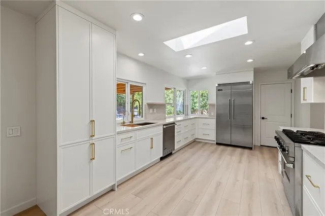a kitchen with white cabinets and wooden floor