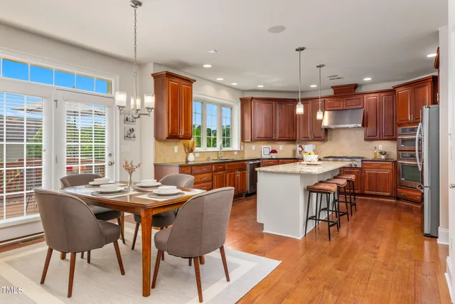 a kitchen with stainless steel appliances granite countertop a stove a refrigerator a kitchen island a dining table and chairs