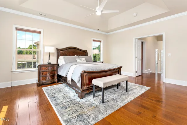 a bedroom with a bed a dresser and wooden floor
