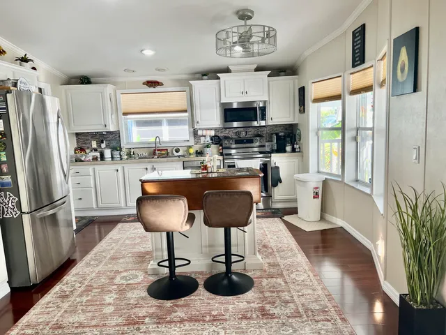a kitchen with stainless steel appliances granite countertop a refrigerator a stove a sink dishwasher a dining table and chairs with wooden floor