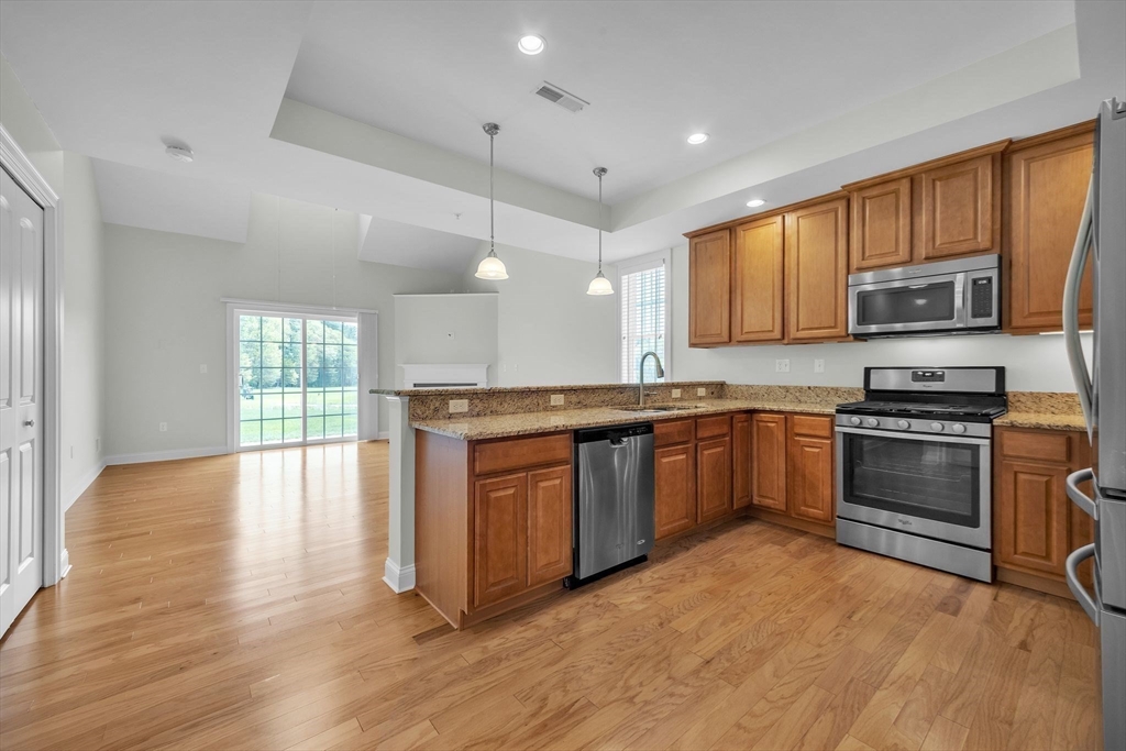 53 Baldwin Road, Unit 1401 Billerica, MA 01821 - Photo 13 of 32 a kitchen with stainless steel appliances kitchen island granite countertop a stove a sink and a microwave