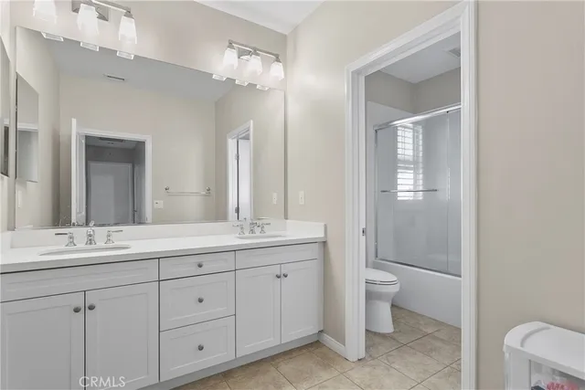 a spacious bathroom with a double vanity sink a toilet and a mirror
