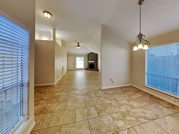 an empty room with windows and fireplace