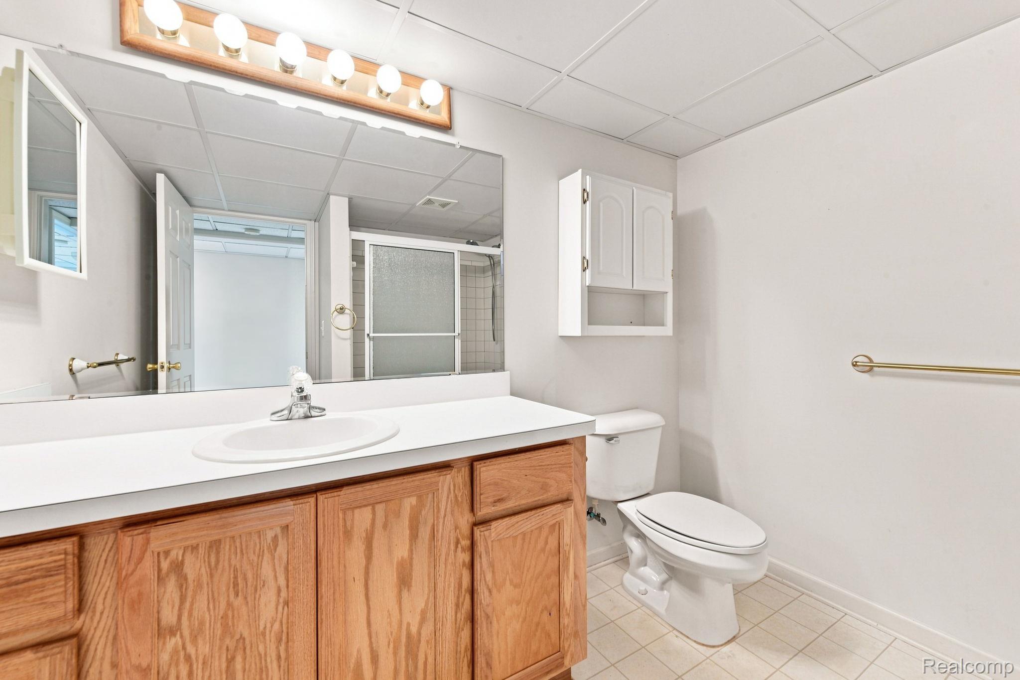 493 Harvard Drive Romeo, MI 48065 - Photo 23 of 36 Vanity with wood-finish cabinetry and integrated sink, full-width mirror, overhead vanity lighting, and wall-mounted storage cabinet