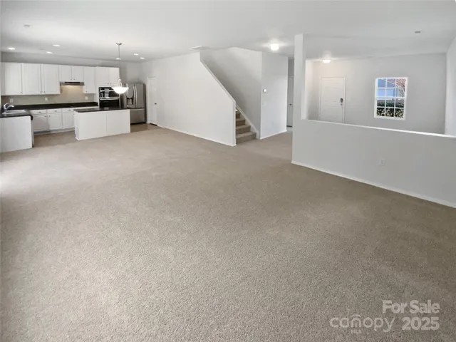 an empty room with kitchen view and a refrigerator