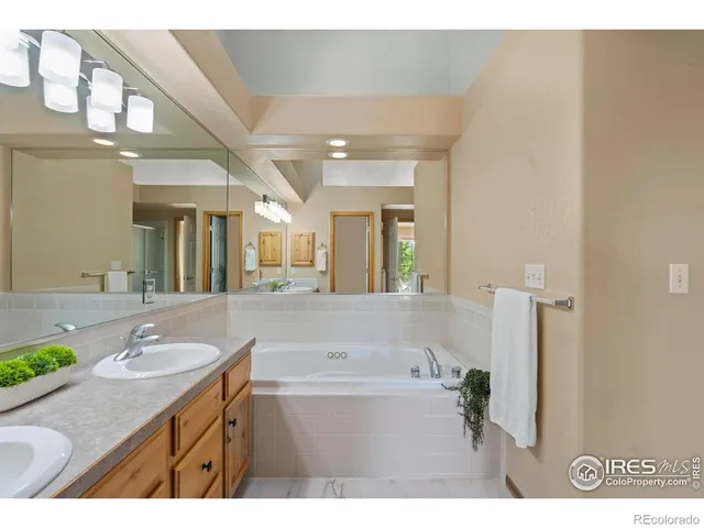 a bathroom with a granite countertop sink a bathtub a mirror and vanity