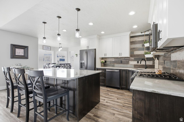 560 East Lower Rock Creek Road Inkom, ID 83245 - Photo 13 of 44 Spacious kitchen featuring a large island with seating, white shaker-style upper cabinetry, dark lower cabinetry, wood-finish flooring, and quartzite countertop