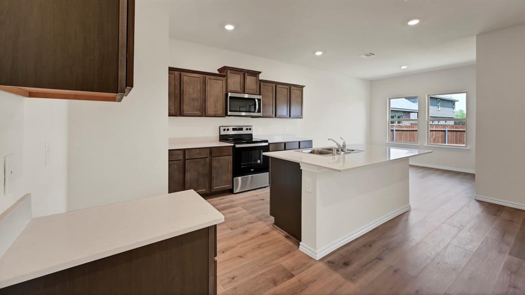 4012 Ripplewood Drive Lindale, TX 75771 - Photo 20 of 37 Contemporary kitchen featuring dark wood-finish cabinetry, light-toned countertops, and stainless steel appliances