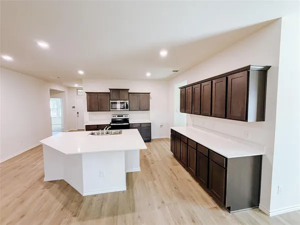 a large kitchen with stainless steel appliances kitchen island a large counter top and a wooden floor