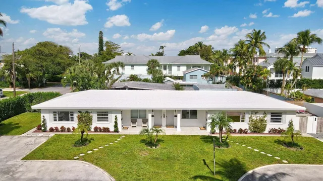 a view of a white house with a yard table and chairs under an umbrella