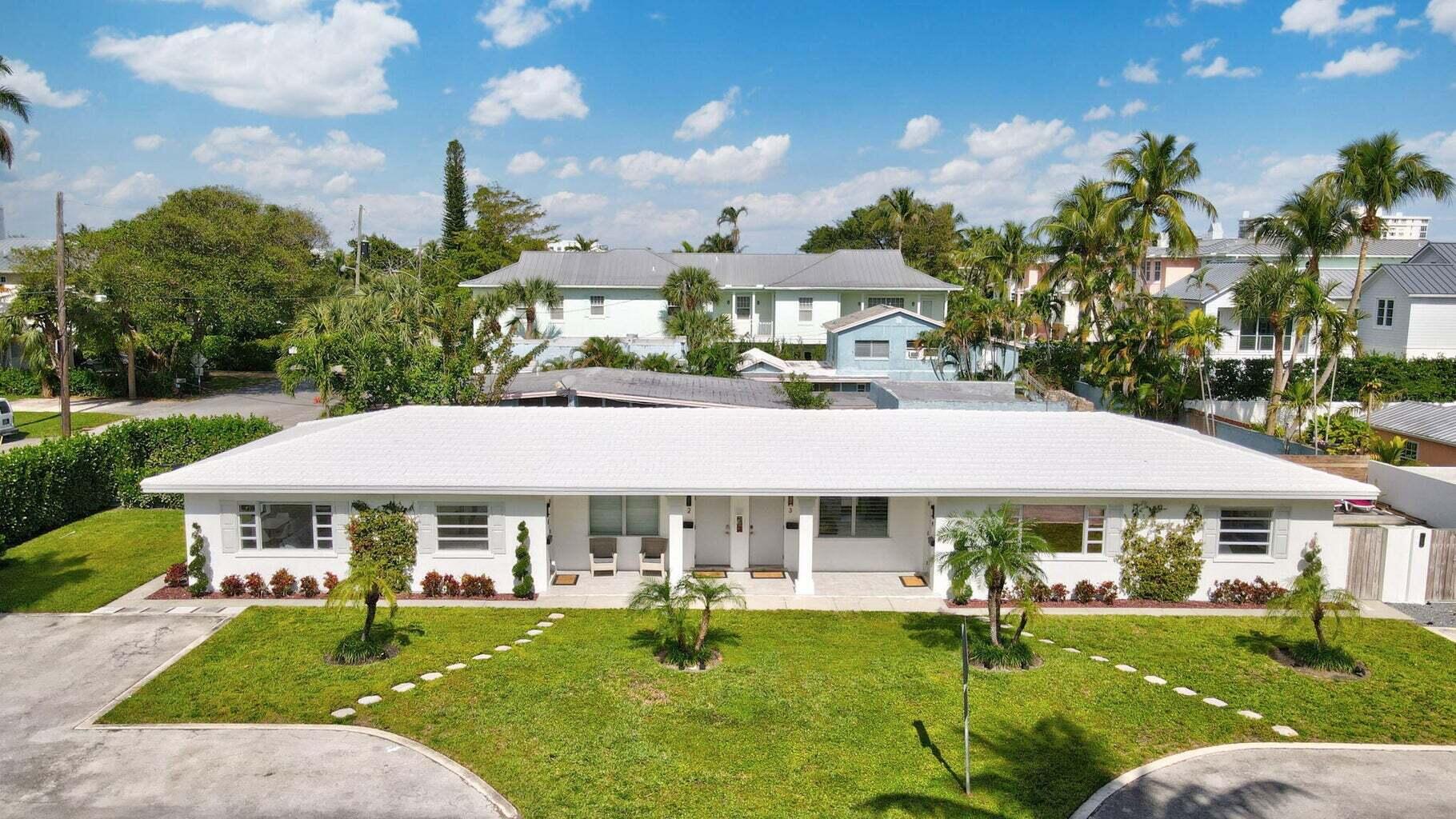 711 Southeast 2nd Street, Unit 4 Delray Beach, FL 33483 - Photo 2 of 23 a view of a white house with a yard table and chairs under an umbrella