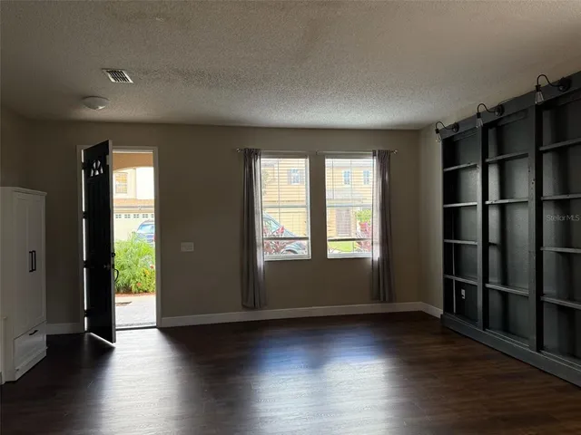 an empty room with wooden floor and windows