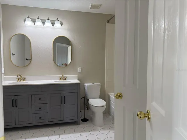 a bathroom with a double vanity sink toilet and a mirror