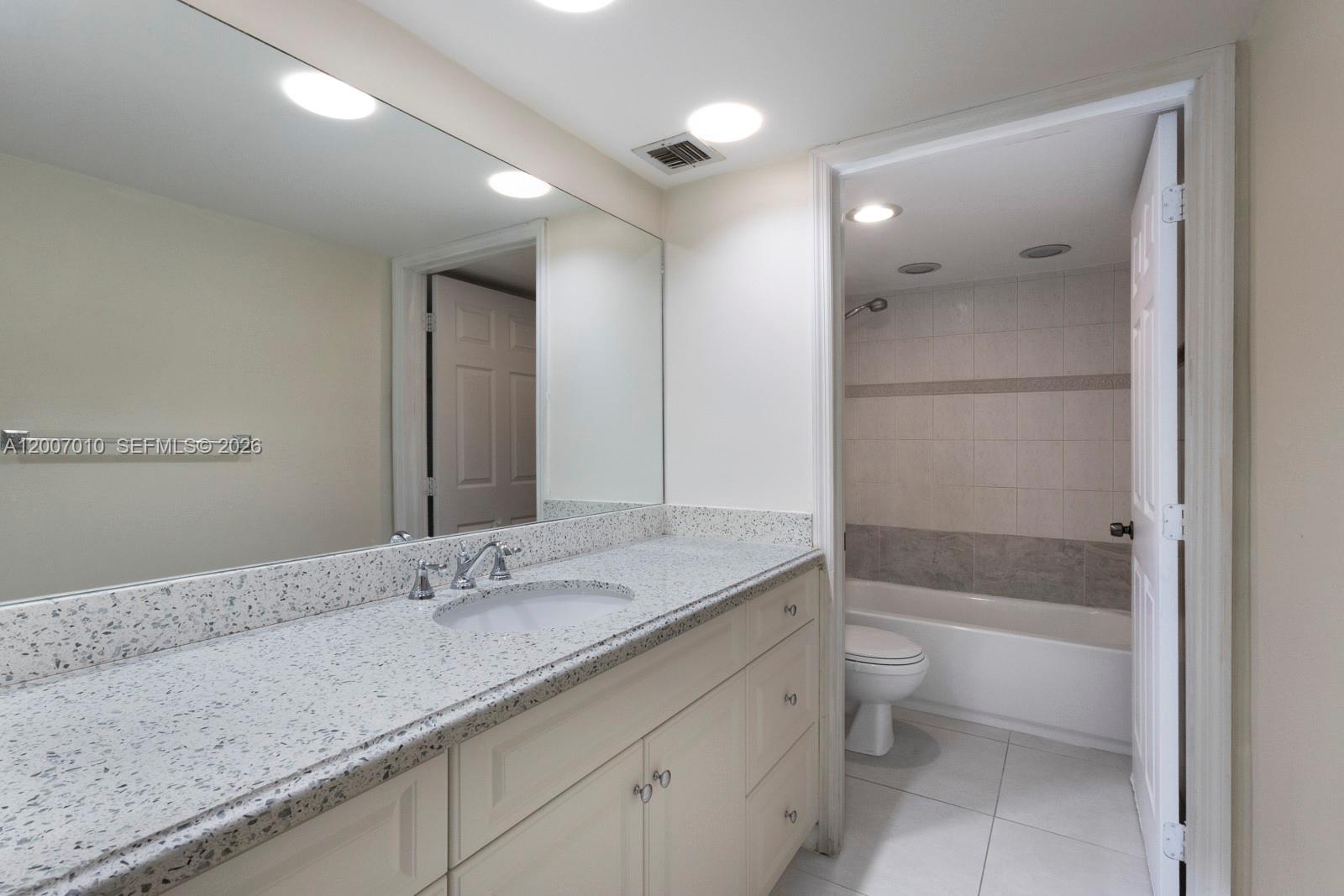 10855 Southwest 112th Avenue, Unit 211 Miami, FL 33176 - Photo 5 of 23 a bathroom with a granite countertop sink a toilet and shower