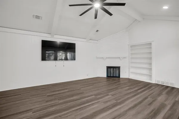 a view of a room with wooden floor a ceiling fan and windows