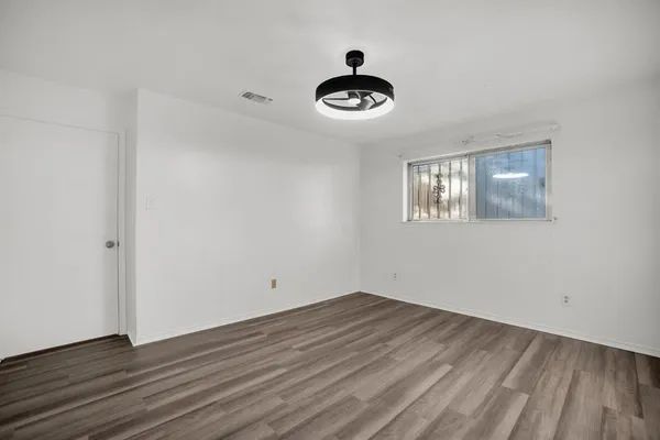a view of a room that has wooden floor and a window