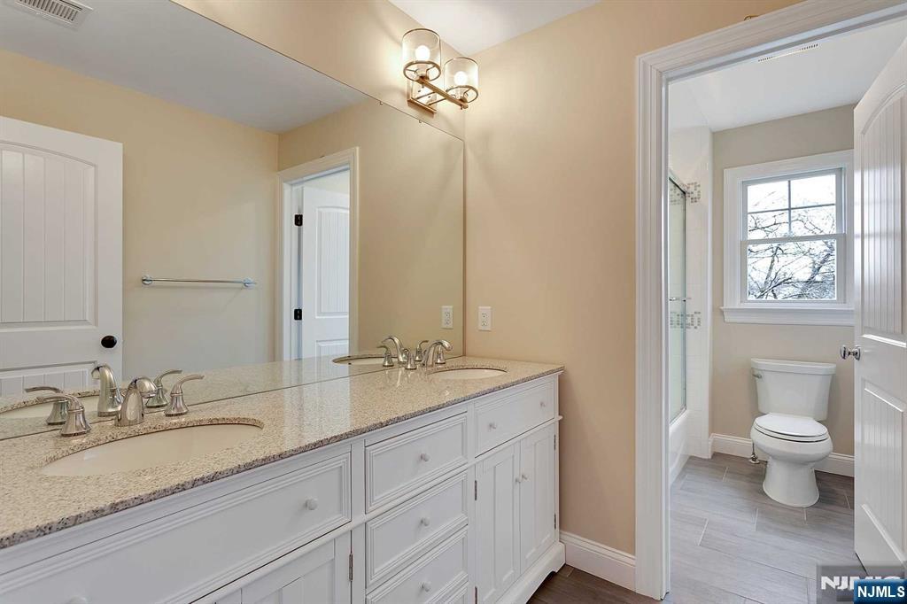 582 Green Valley Road Paramus, NJ 07652 - Photo 17 of 25 a bathroom with a granite countertop sink a toilet and a mirror