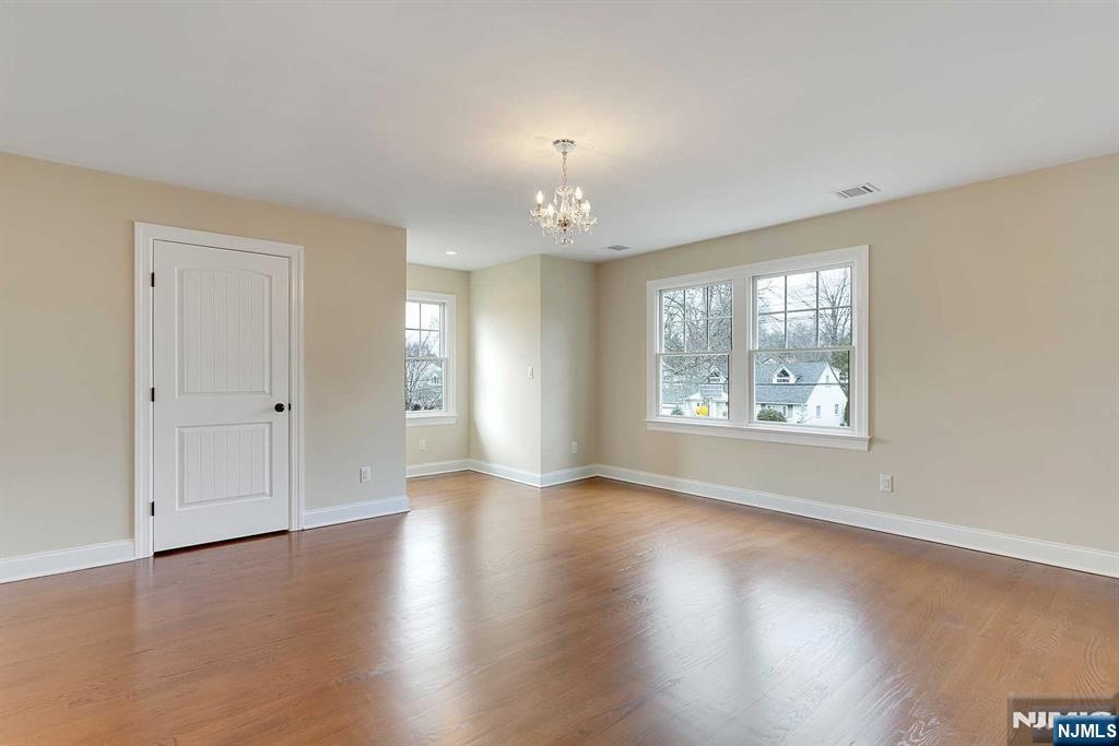 582 Green Valley Road Paramus, NJ 07652 - Photo 18 of 25 an empty room with wooden floor chandelier and windows
