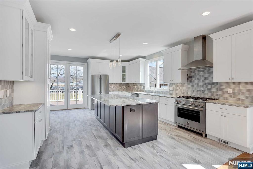 582 Green Valley Road Paramus, NJ 07652 - Photo 6 of 25 a kitchen with stainless steel appliances granite countertop a stove top oven a sink dishwasher a refrigerator and white cabinets with wooden floor